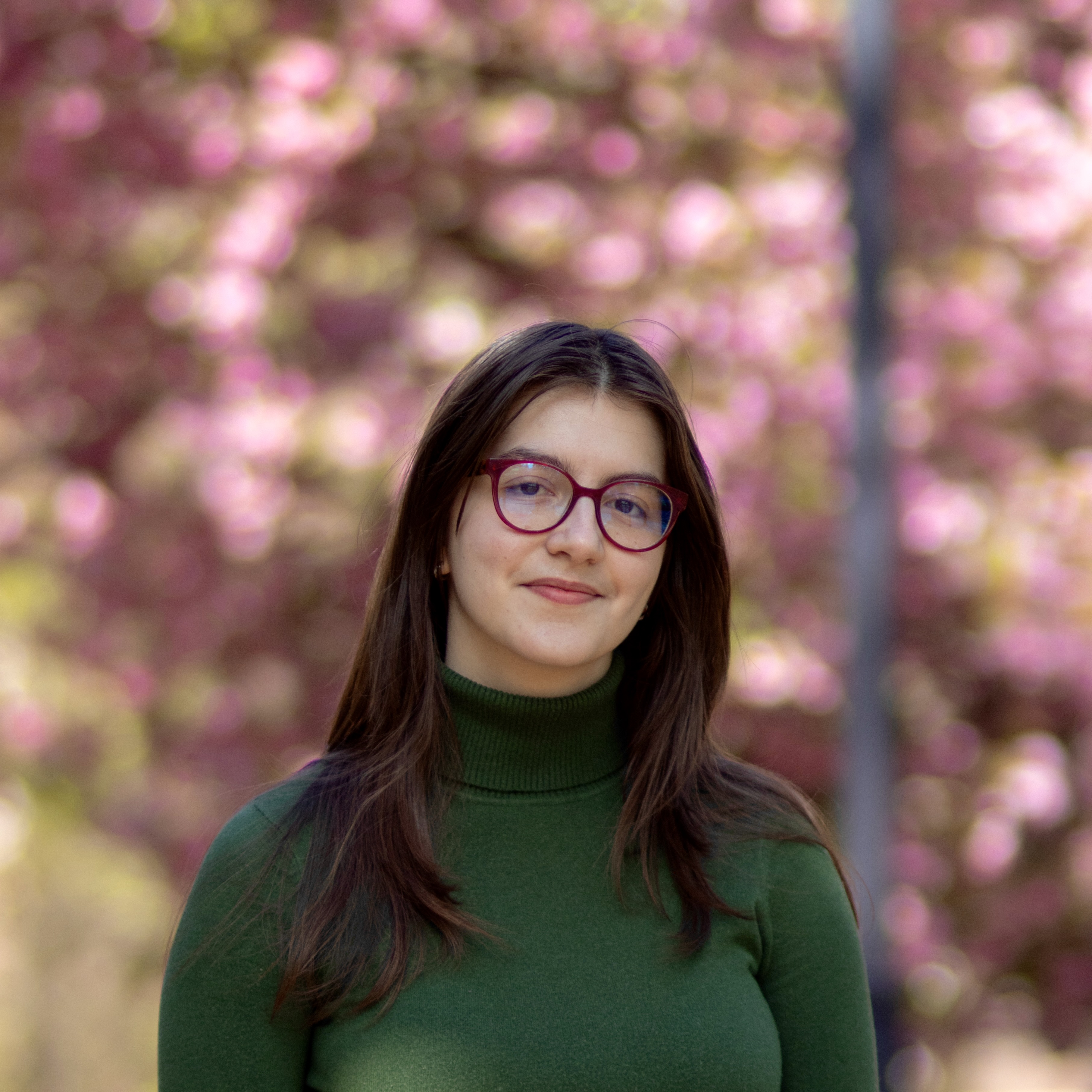 Photograph of Nada Stojanovic in professional attire against a bright cherry tree background.